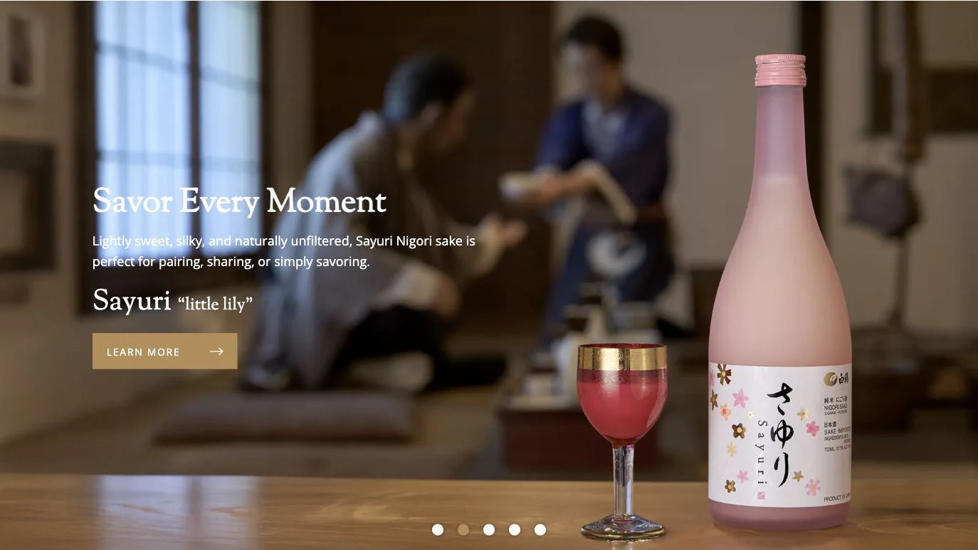 Hakutsuru homepage hero showing Sayuri sake in a warmly lit room where people are sharing a drink