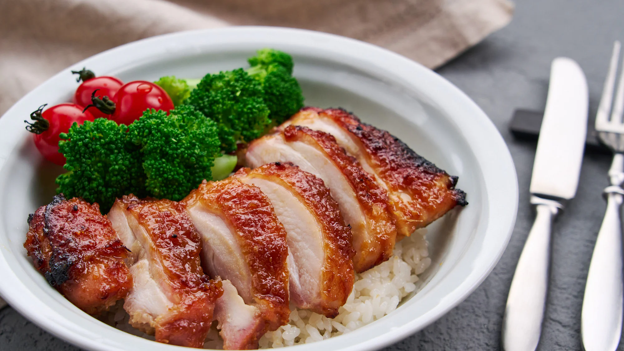 ご飯に盛り付け、ブロッコリーとトマトを添えた味噌照り焼きチキン