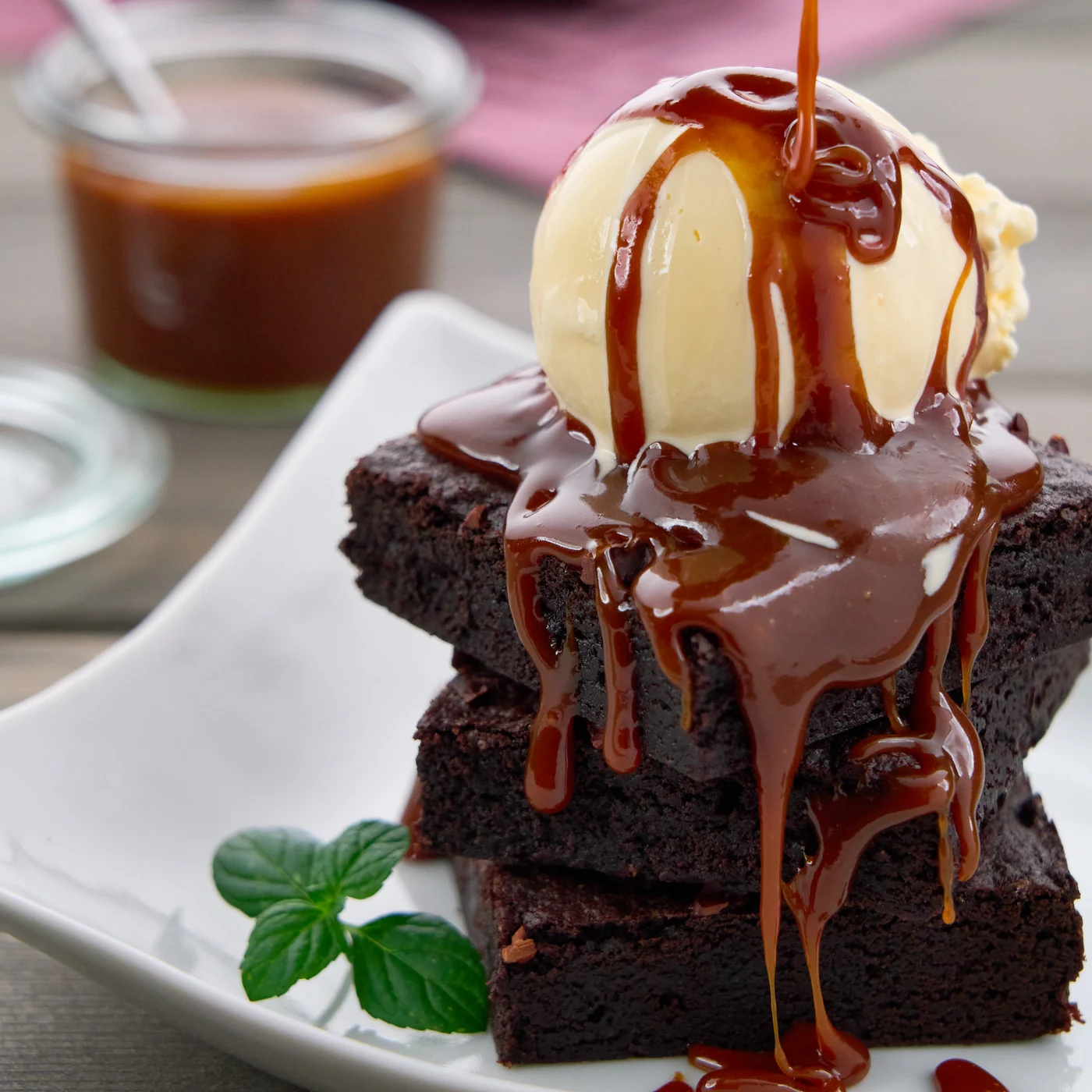 Miso caramel sauce being poured over vanilla ice cream and chocolate brownies