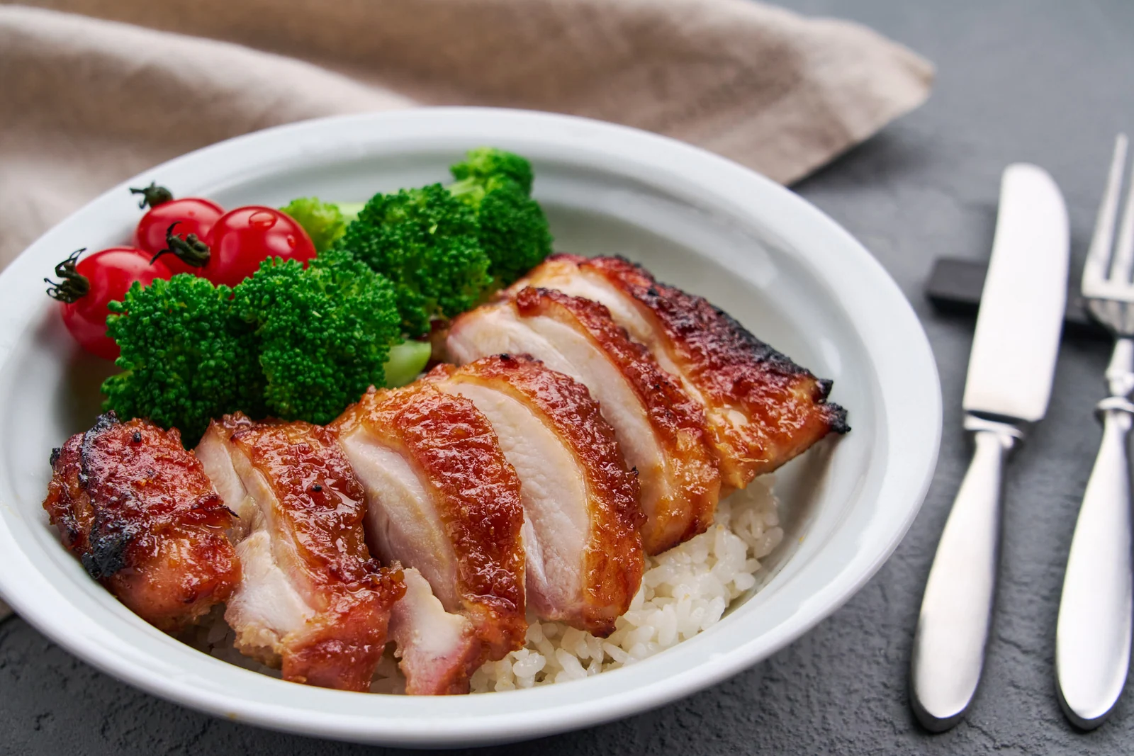 ご飯に盛り付け、ブロッコリーとトマトを添えた味噌照り焼きチキン