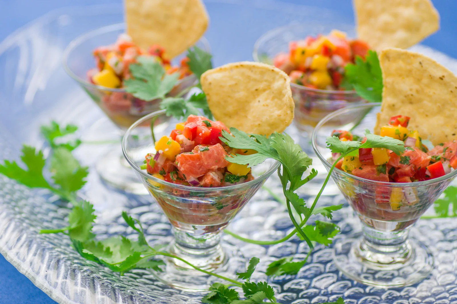 Tuna appetizers presented in small glasses with tortilla chips and herbs